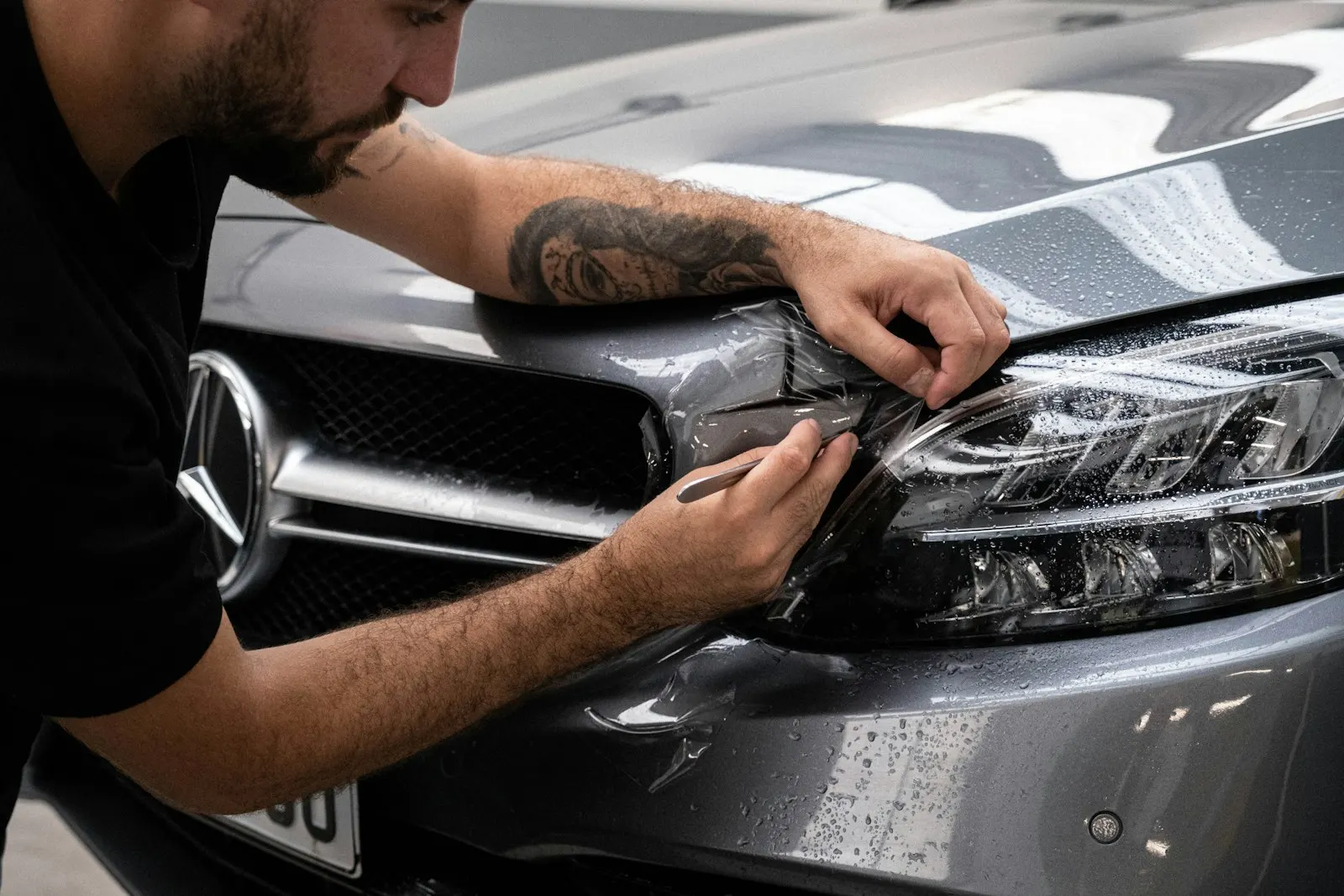 Hender fjerner folie fra fronten på en Mercedes